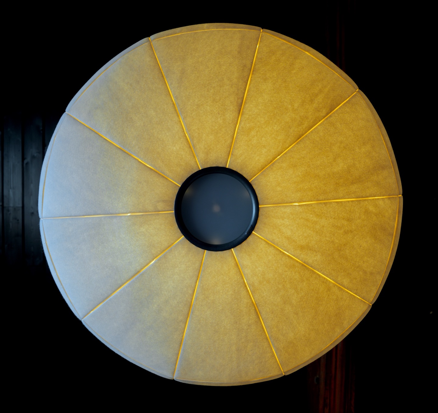 Lit wool pendant seen from below, twelve panels radiating from a dark central ring.