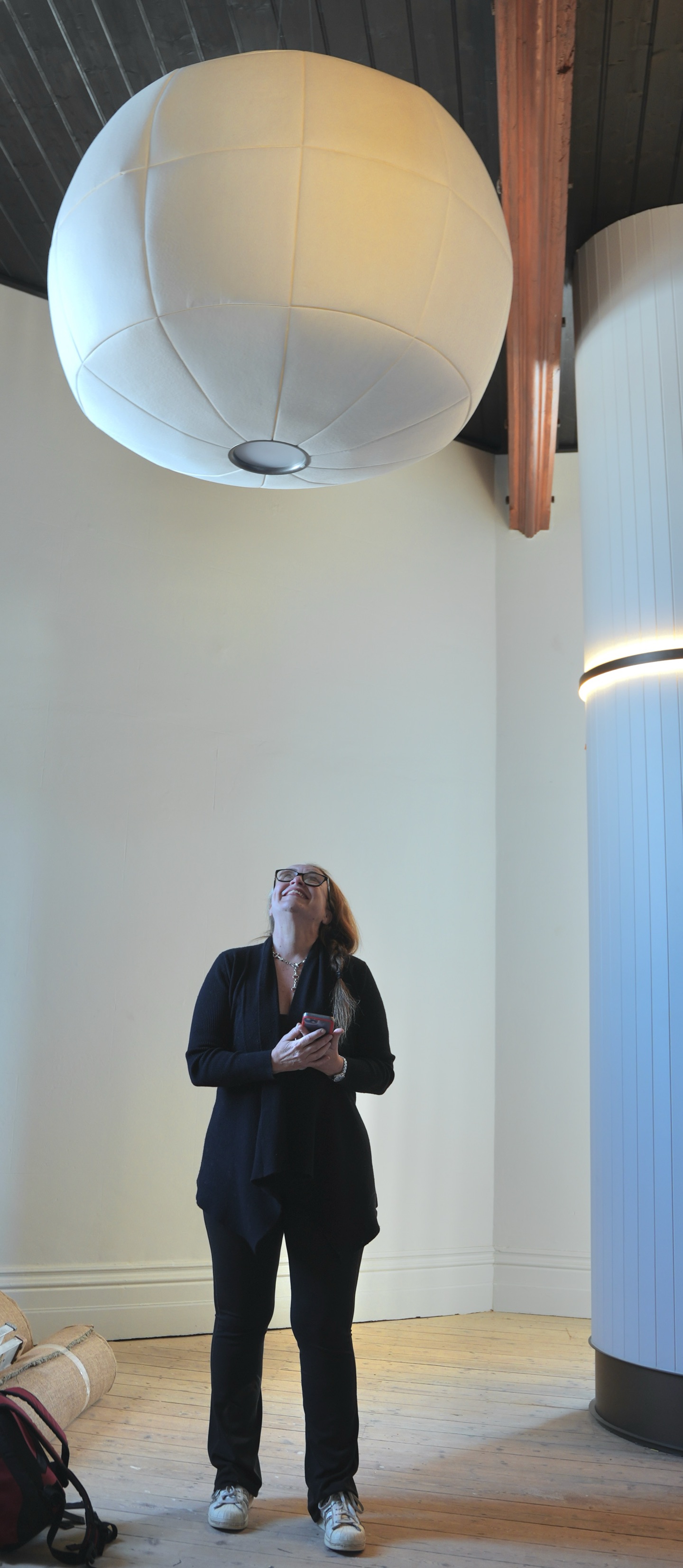 The Vantage GM, Bobbie-Jane Skewes, poses below a large unlit wool pendant hanging below a dark timber ceiling.